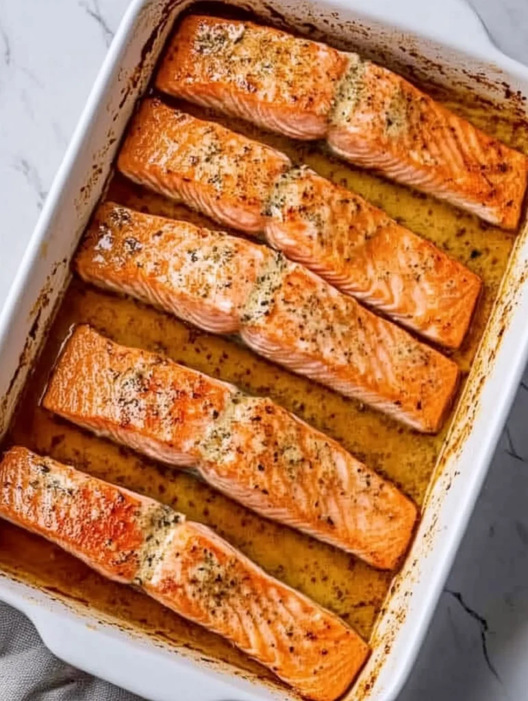 baked salmon fillets neatly arranged in a dish, showcasing the perfectly cooked texture with a golden-brown top.